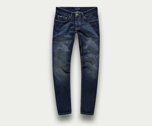 De N01 Slim Dark Indigo Used jeans van Blue Rivet Jeans zijn gemaakt van stretch denim en hebben een knoop- en ritssluiting. Deze premium jeans hebben subtiele vervagingen op de dijen en knieën, vijf zakken en contrasterende stiksels, allemaal tegen een lichtgrijze achtergrond.