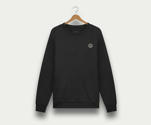 De N01 Sweat Anthracite van Blue Rivet Jeans is een zwarte crewneck sweater van biologisch katoen, afgebeeld op een houten hanger tegen een lichte achtergrond. Deze premium sweater voor heren heeft een klein rond logo op de linkerborst.