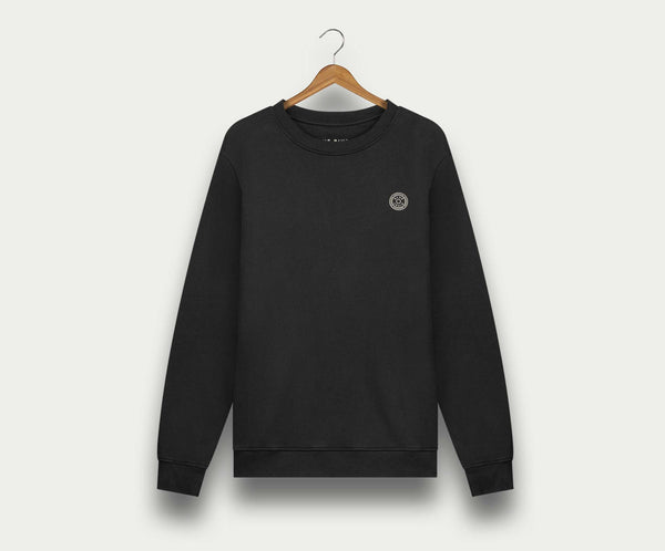 De N01 Sweat Anthracite van Blue Rivet Jeans is een zwarte crewneck sweater van biologisch katoen, afgebeeld op een houten hanger tegen een lichte achtergrond. Deze premium sweater voor heren heeft een klein rond logo op de linkerborst.