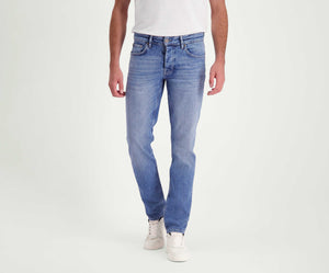 Een persoon draagt de N01 Slim Stone Bleached jeans van Blue Rivet Jeans en witte sneakers tegen een effen witte achtergrond.