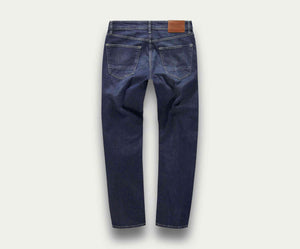 Achterkant van de N01 Straight Indigo Used jeans van Blue Rivet Jeans, met zichtbare stiksels en een bruine leren patch op de tailleband, afgebeeld op een lichtgrijze achtergrond.