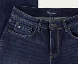 Close-up van The N01 Straight Indigo Used jeans van Blue Rivet Jeans, met zichtbare stiksels en een merklabel op de tailleband. Deze straight-fit stretch denim jeans zijn voorzien van metalen klinknagels en hebben een klein muntzakje aan de voorkant. Ze zijn kunstig gerangschikt op een wit oppervlak.