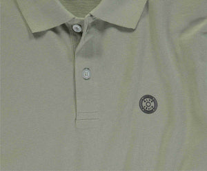 Close-up van The N01 Polo Seagrass van Blue Rivet Jeans, met een lichtgroene textuurstof en korte mouwen. Deze heren polo heeft twee knopen bij de kraag en een cirkelvormig geborduurd logo op de linkerborst.