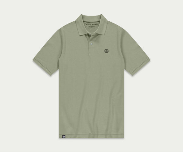 Introductie van de N01 Polo Seagrass van Blue Rivet Jeans: een lichtgroene polo met korte mouwen en een subtiel logo op de linkerborst. Dit shirt is ontworpen met een klassieke kraag en een sluiting met drie knopen, gepresenteerd tegen een effen witte achtergrond.