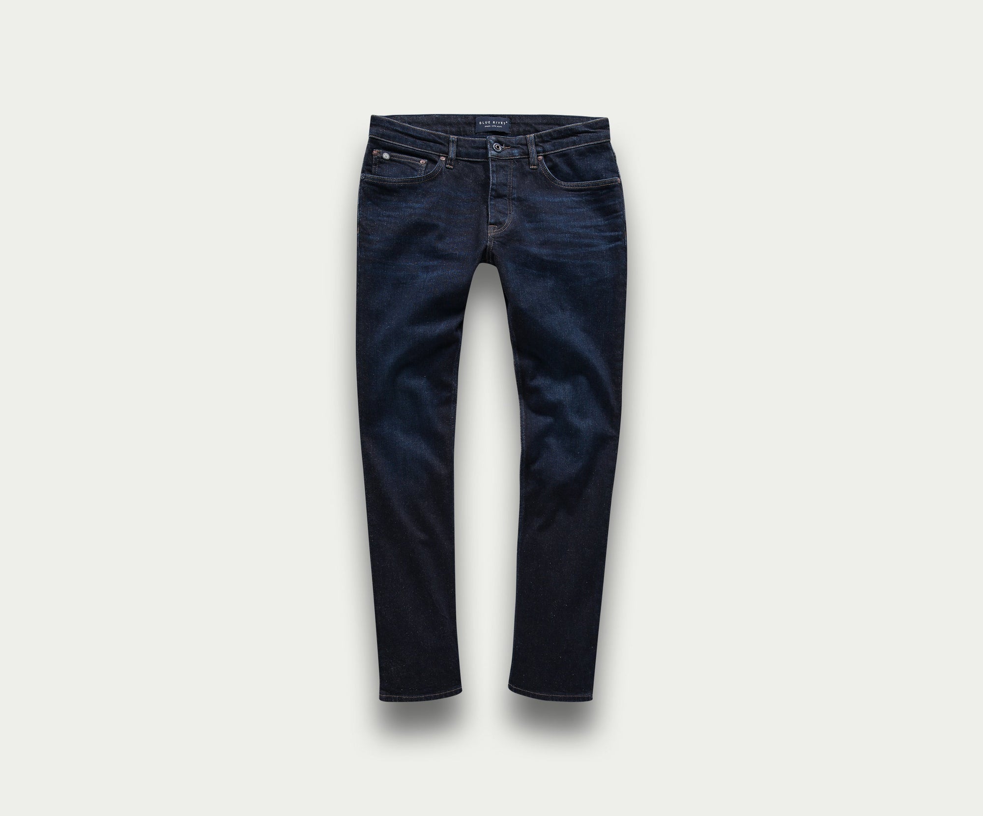 Een premium paar The N01 Slim Dark Indigo jeans van Blue Rivet Jeans, met een slim fit die plat ligt tegen een lichte achtergrond. Deze stijlvolle jeans hebben een klassiek five-pocket design, zichtbare stiksels en een vleugje stretch voor extra comfort.