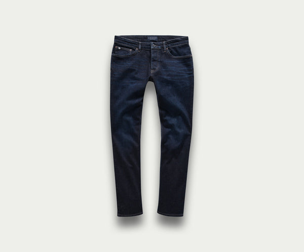 Een premium paar The N01 Slim Dark Indigo jeans van Blue Rivet Jeans, met een slim fit die plat ligt tegen een lichte achtergrond. Deze stijlvolle jeans hebben een klassiek five-pocket design, zichtbare stiksels en een vleugje stretch voor extra comfort.