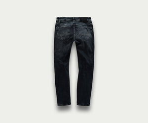 Achteraanzicht van The N01 Slim Blue Black Used jeans van Blue Rivet Jeans tegen een effen lichte achtergrond. De jeans heeft een subtiele vervaagde textuur en twee achterzakken.