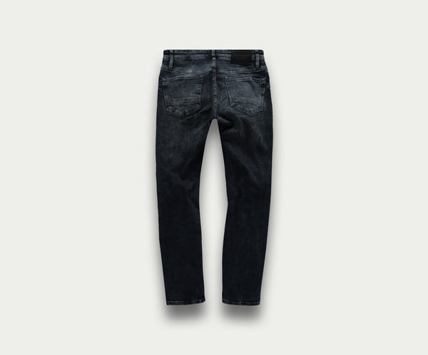 Achteraanzicht van The N01 Slim Blue Black Used jeans van Blue Rivet Jeans tegen een effen lichte achtergrond. De jeans heeft een subtiele vervaagde textuur en twee achterzakken.
