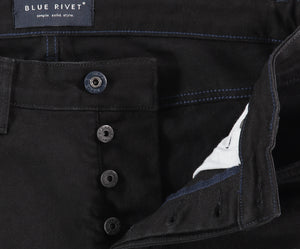 Close-up van The N01 Slim Black premium denim jeans, met een zichtbare knoopsluiting en blauwe stiksels. Het Blue Rivet Jeans merklabel is in de tailleband genaaid, wat de kwaliteit van deze spijkerbroek benadrukt.