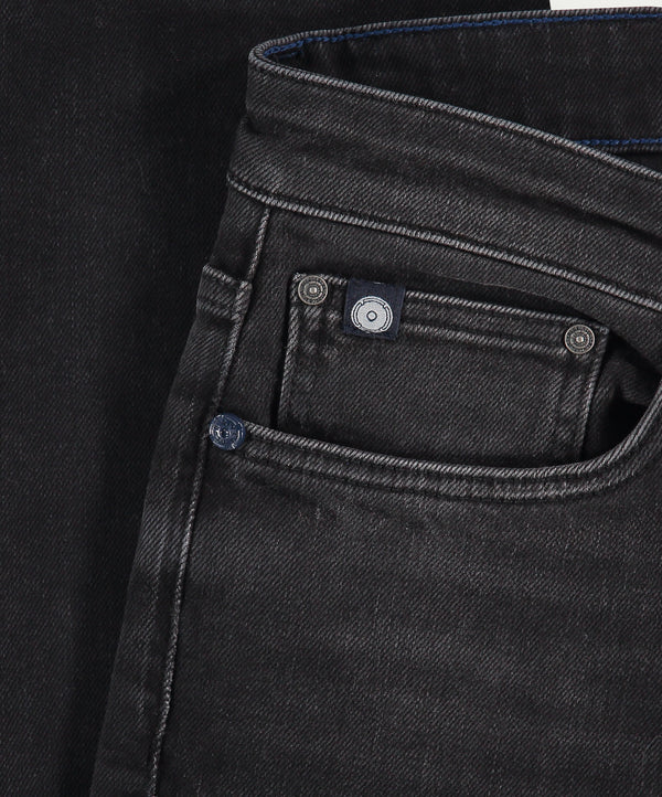 Close-up van Blue Rivet Jeans' The N01 Slim Black Used denim, met de nadruk op de voorzak en taille. De premium stof heeft een lichte glans met zichtbare randstiksels, geaccentueerd door twee metalen klinknagels bij de zak.
