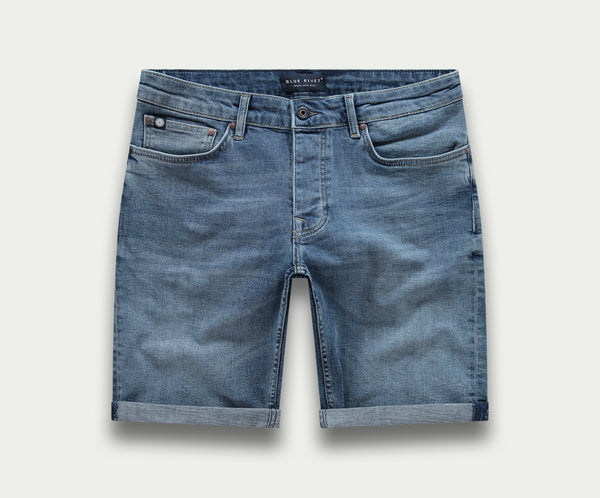 Een paar The N01 Short Indigo Used by Blue Rivet Jeans, met een klassiek five-pocket-ontwerp, knoopsluiting en gerolde manchetten, afgebeeld op een effen witte achtergrond.