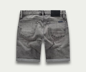 De achterkant van "The N01 Short Light Grey Used" van Blue Rivet Jeans toont een paar grijze denim shorts met opgerolde zomen. Deze shorts, ook wel "korte broek" genoemd, hebben twee achterzakken en een zwart taillebandlabel. De licht vervaagde stof versterkt hun casual, versleten uiterlijk.