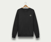 De N01 Sweat Anthracite van Blue Rivet Jeans is een zwarte crewneck sweater van biologisch katoen, afgebeeld op een houten hanger tegen een lichte achtergrond. Deze premium sweater voor heren heeft een klein rond logo op de linkerborst.