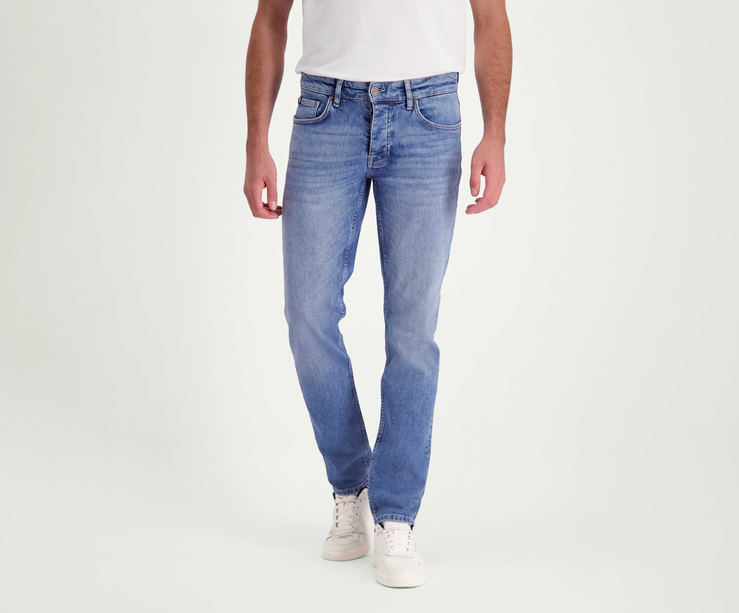 Een persoon draagt de N01 Slim Stone Bleached jeans van Blue Rivet Jeans en witte sneakers tegen een effen witte achtergrond.