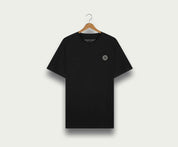 Een zwarte "The N01 Tee Black" van Blue Rivet Jeans op een houten hanger tegen een lichte achtergrond. Dit regular fit shirt heeft een klein rond logo op de linkerborst.