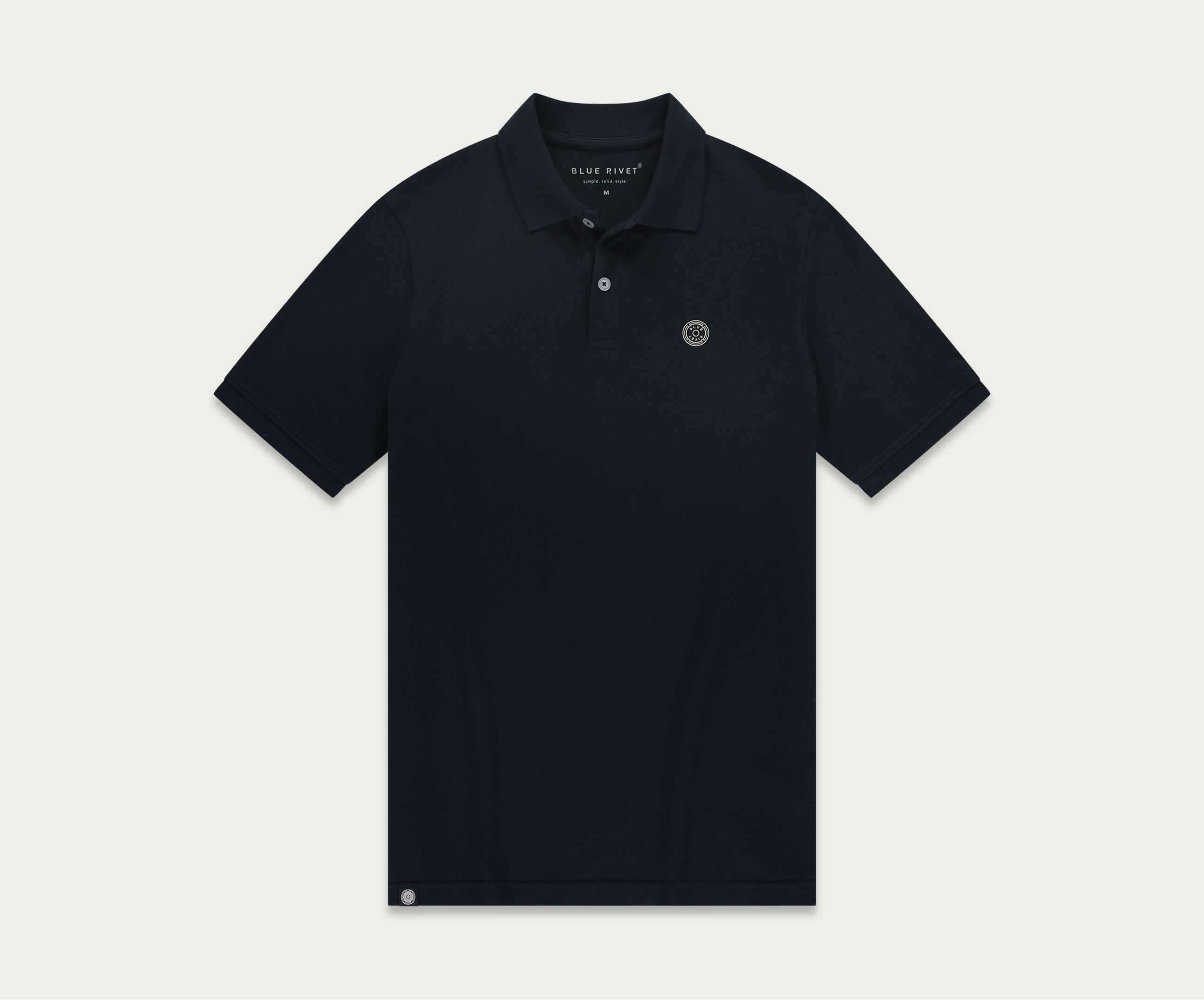 De N01 Polo Navy van Blue Rivet Jeans is een poloshirt voor heren met korte mouwen, een kraag en een knoopsluiting. Op de linkerborst is een klein, rond logo geborduurd. Het shirt wordt plat gelegd tegen een effen, lichte achtergrond.