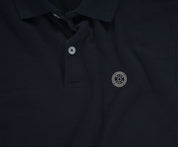 De marineblauwe N01 Polo van Blue Rivet Jeans heeft een kraag met knopen en een gestileerd zilveren cirkelvormig embleem op de linkerborst. De polo heeft korte mouwen.