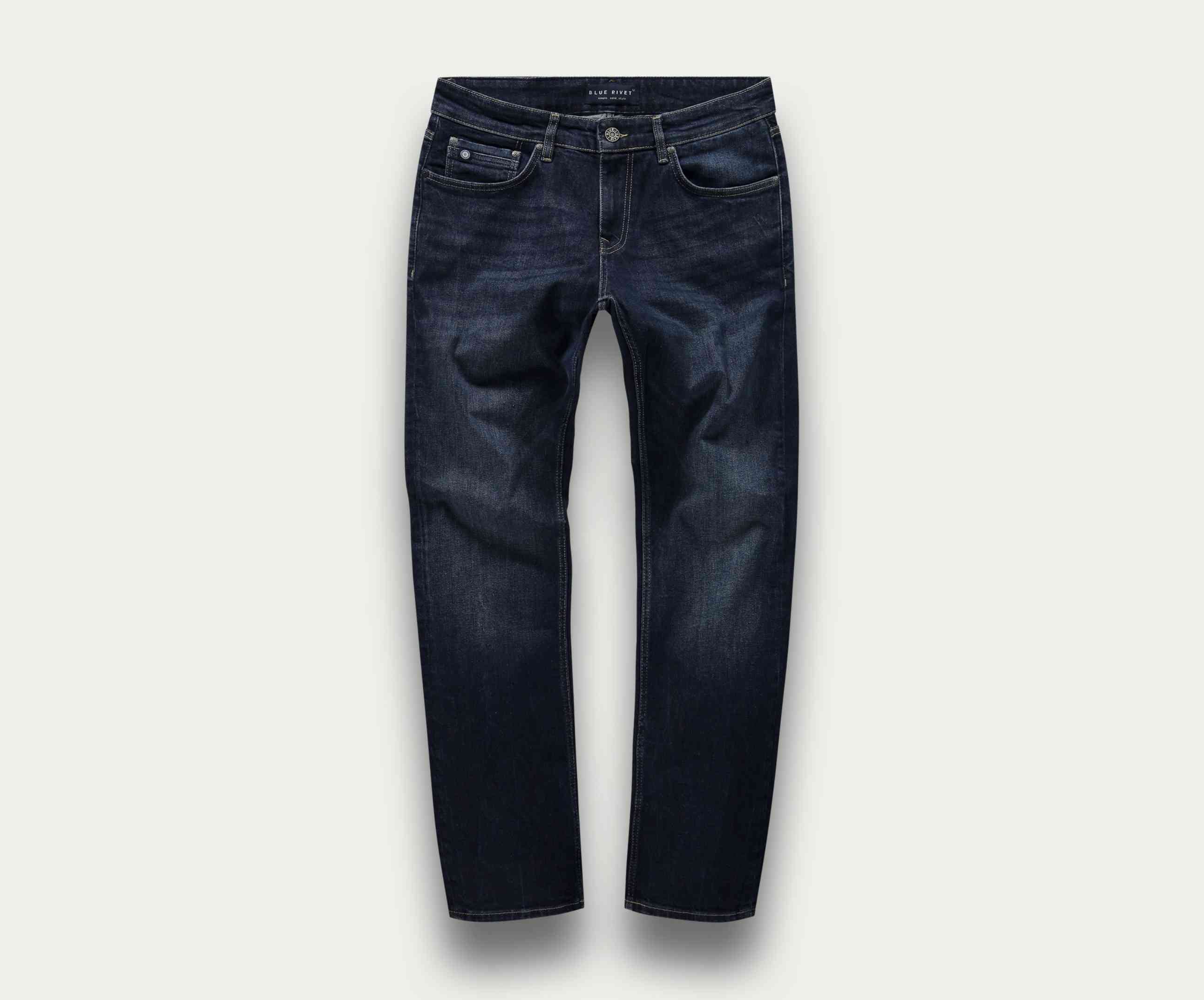 Een paar The N01 Straight Dark Indigo Used jeans van Blue Rivet Jeans wordt getoond tegen een lichte achtergrond, bekeken vanaf de voorkant. Deze jeans hebben een traditionele five-pocket-stijl met knoop- en ritssluiting, wat zorgt voor een subtiele stretch voor verbeterd comfort.