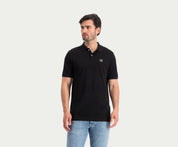Een persoon die de N01 Polo Anthracite and Blue Rivet Jeans draagt, staat tegen een effen witte achtergrond, kijkt naar links en straalt zomerse chic uit.