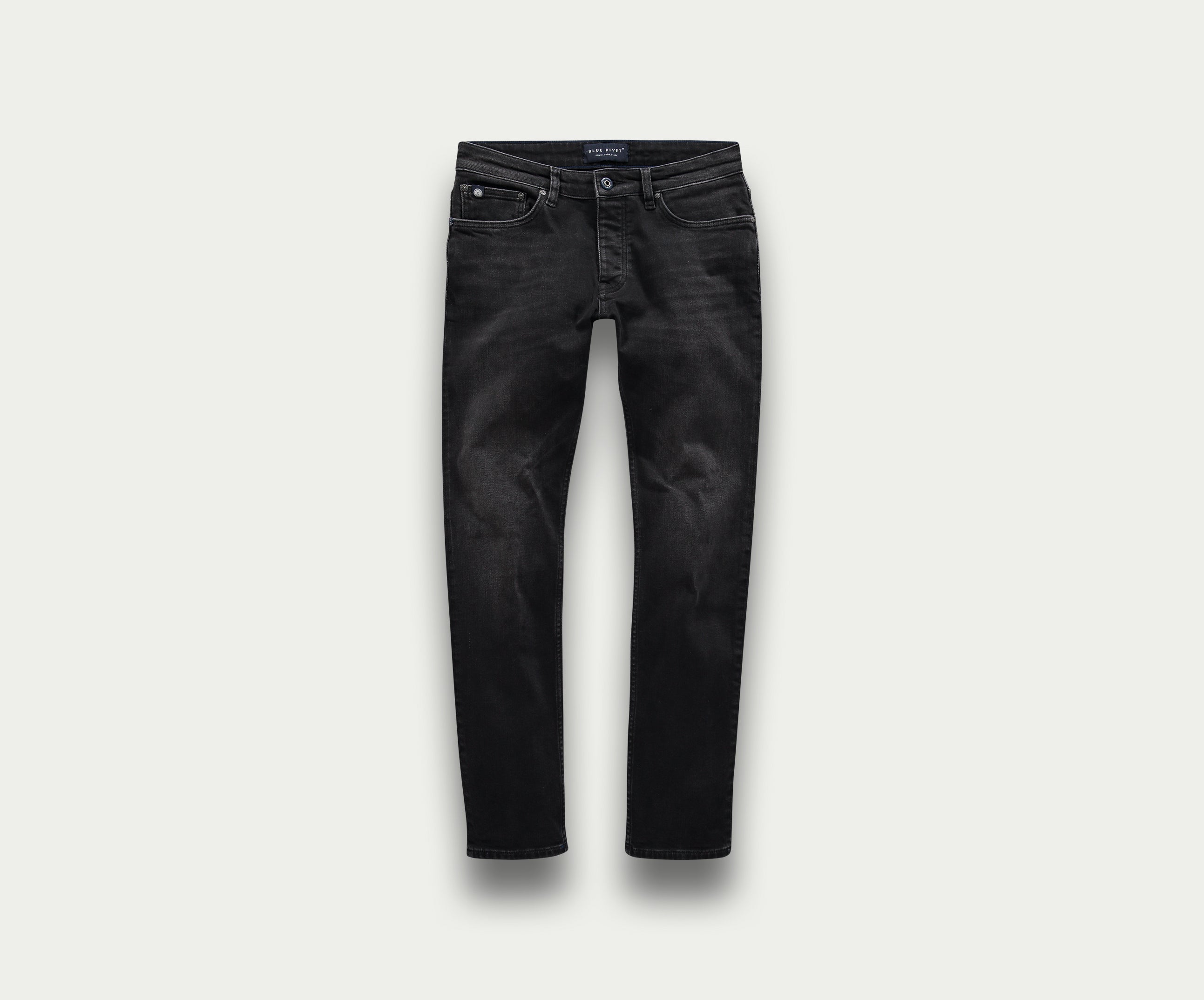 De N01 Slim Black Used jeans van Blue Rivet Jeans worden getoond op een lichtgrijze achtergrond, met een tijdloos five-pocket design en een knoopsluiting bij de tailleband. De denim heeft een licht vervaagde look, wat zorgt voor die ideale gedragen look.