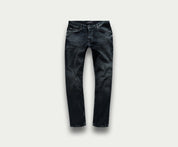 Een paar "The N01 Slim Blue Black Used" jeans van Blue Rivet Jeans wordt getoond op een lichtgrijze achtergrond. Deze spijkerbroek heeft subtiele vervagings- en kreukdetails met standaardzakken en riemlussen, wat zorgt voor een klassieke en veelzijdige uitstraling.