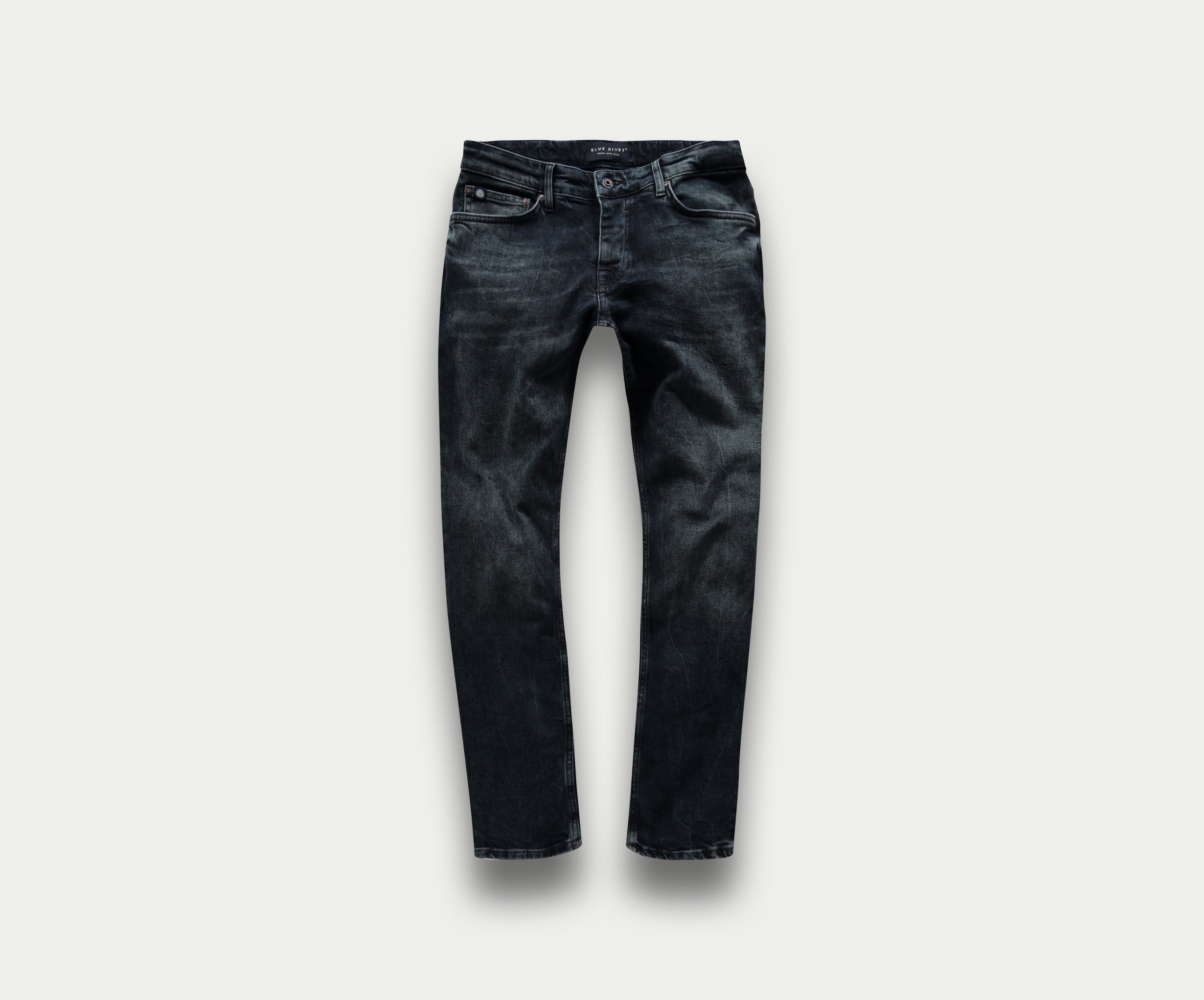 Een paar "The N01 Slim Blue Black Used" jeans van Blue Rivet Jeans wordt getoond op een lichtgrijze achtergrond. Deze spijkerbroek heeft subtiele vervagings- en kreukdetails met standaardzakken en riemlussen, wat zorgt voor een klassieke en veelzijdige uitstraling.